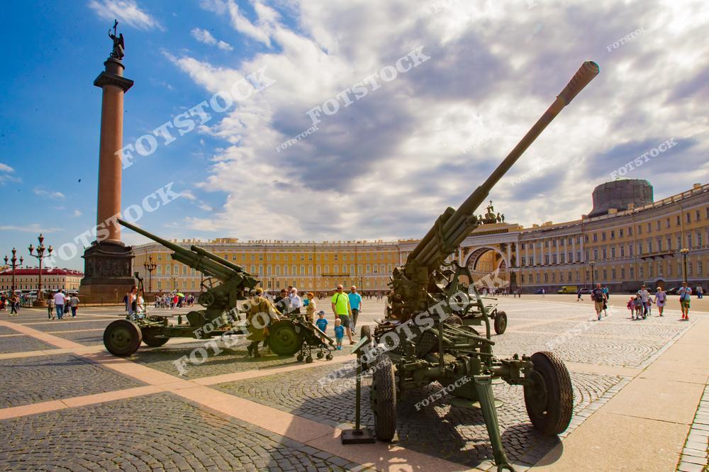 На фотографии изображена выставка военной техники времен Второй мировой войны, расположенная на Дворцовой площади в Санкт-Петербурге. Артиллерийские орудия и другие военные машины, представленные на открытом воздухе, символизируют героизм и память о событиях Великой Отечественной войны. День Победы является важным праздником для города и всей России, и выставка под открытым небом напоминает о значимости этих исторических событий.